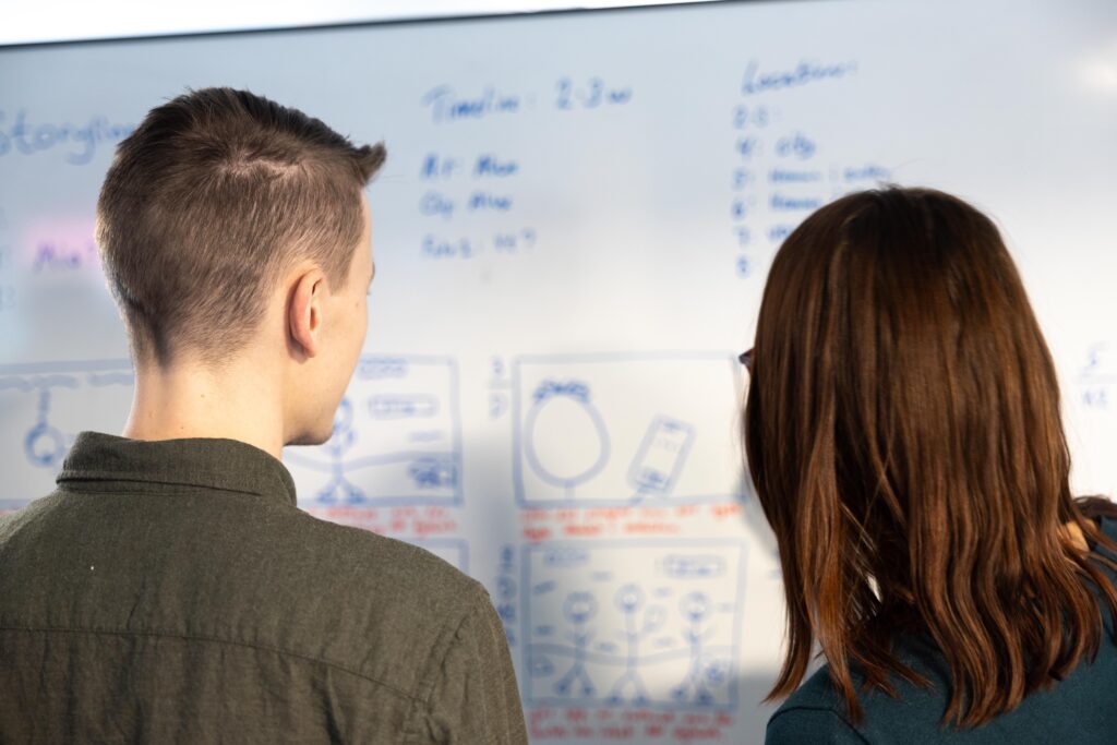 två medarbetare ser på en whiteboard med avancedade skisser på
